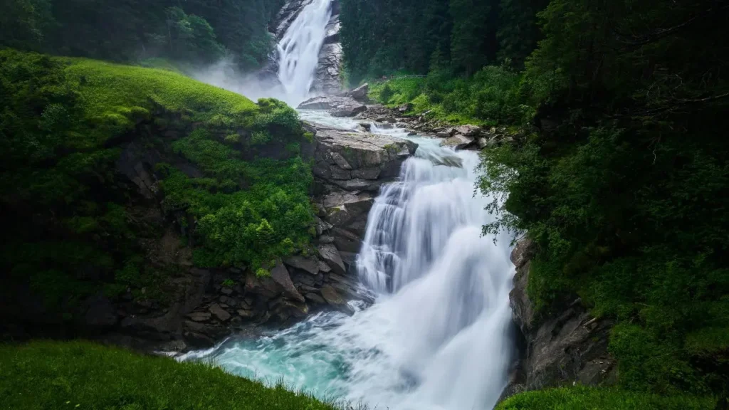 A tall white waterfall surrounded by green jungle plants in Bali