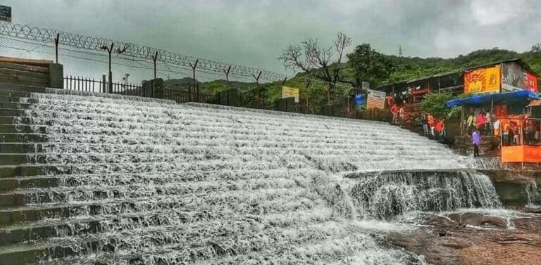 A beautiful wide view of water flowing over the stone steps at Bhushi Dam Lonavala during monsoon