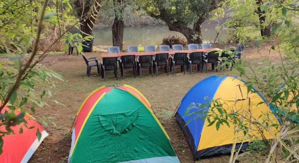 Colorful camping tent set up near the peaceful Mulshi dam waterfall.