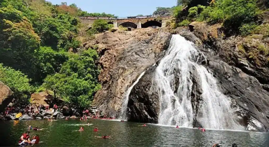 A beautiful full view of Dudhsagar Waterfall in Goa with a train passing on the bridge